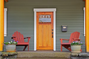 Mission style Stained wood front door with beveled glass surrounded by two Adirondack chairs and flowers